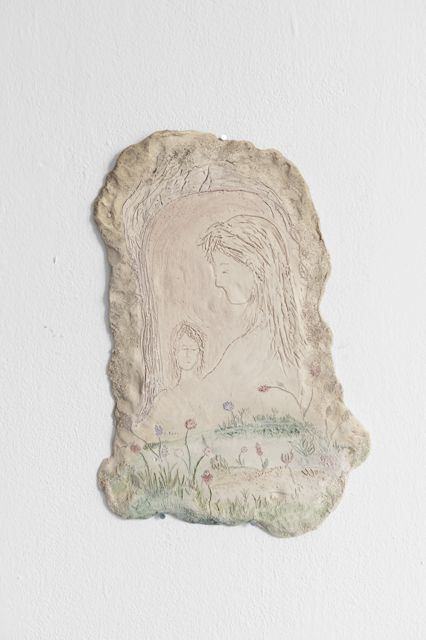 Helles Tonrelief mit eingeritzter Figur und kleinen Blüten am Rand